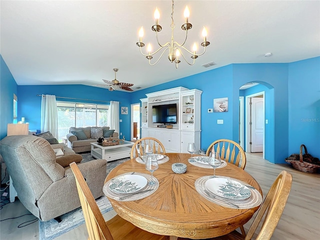 dining room featuring ceiling fan with notable chandelier, light wood-type flooring, and lofted ceiling