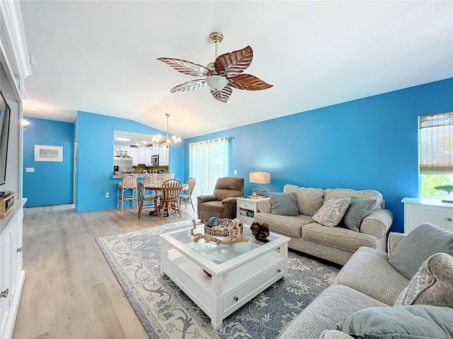 living room with ceiling fan with notable chandelier, light wood-type flooring, and lofted ceiling