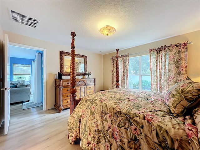 bedroom featuring a textured ceiling and light hardwood / wood-style floors