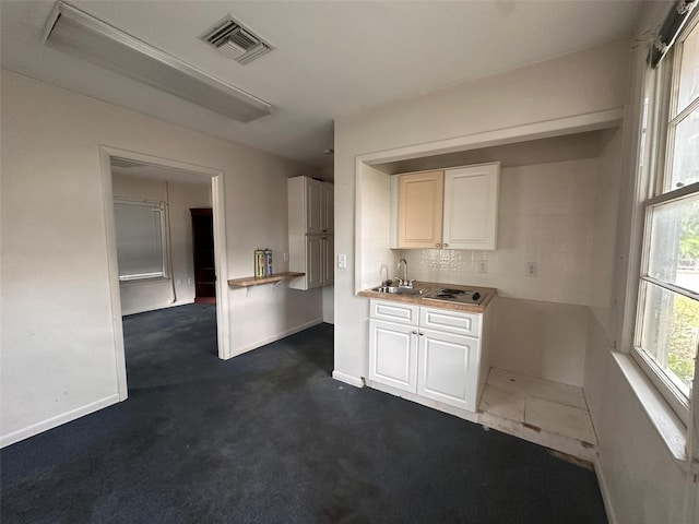 121 Bates Ave SE, Winter Haven, FL 33880 - kitchen with white cabinets, dark colored carpet, and sink