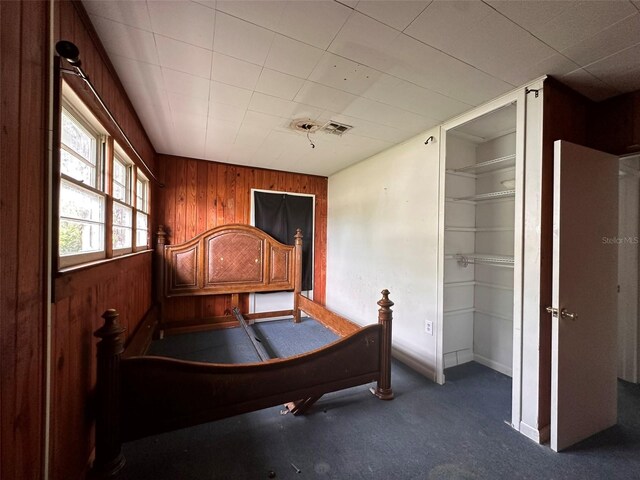 121 Bates Ave SE, Winter Haven, FL 33880 - unfurnished bedroom featuring wooden walls, a closet, and carpet floors