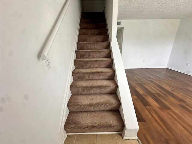 staircase featuring a textured ceiling and hardwood / wood-style floors