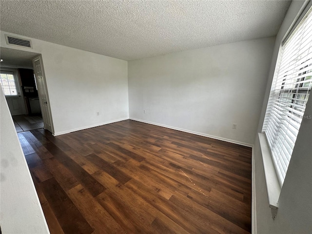 spare room featuring a textured ceiling and dark hardwood / wood-style floors