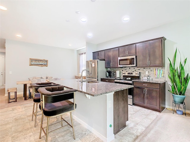 278 Alford Dr, Davenport, FL 33896 - kitchen featuring appliances with stainless steel finishes, a sink, a kitchen island with sink, a breakfast bar, and dark brown cabinets