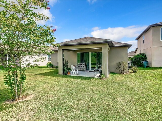 278 Alford Dr, Davenport, FL 33896 - back of property with stucco siding, a patio area, a yard, and a shingled roof