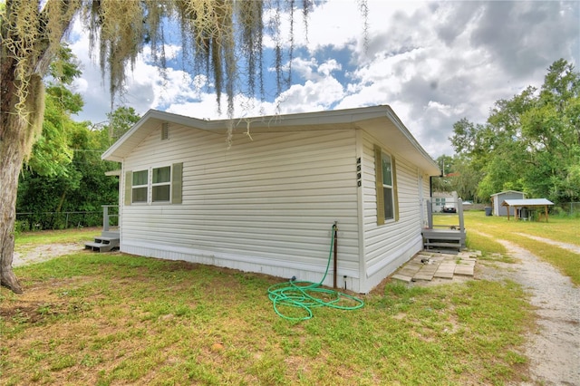 view of home's exterior with a lawn and a storage unit