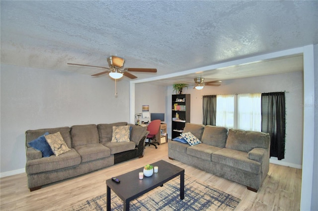 living room featuring light wood-type flooring, a textured ceiling, and ceiling fan