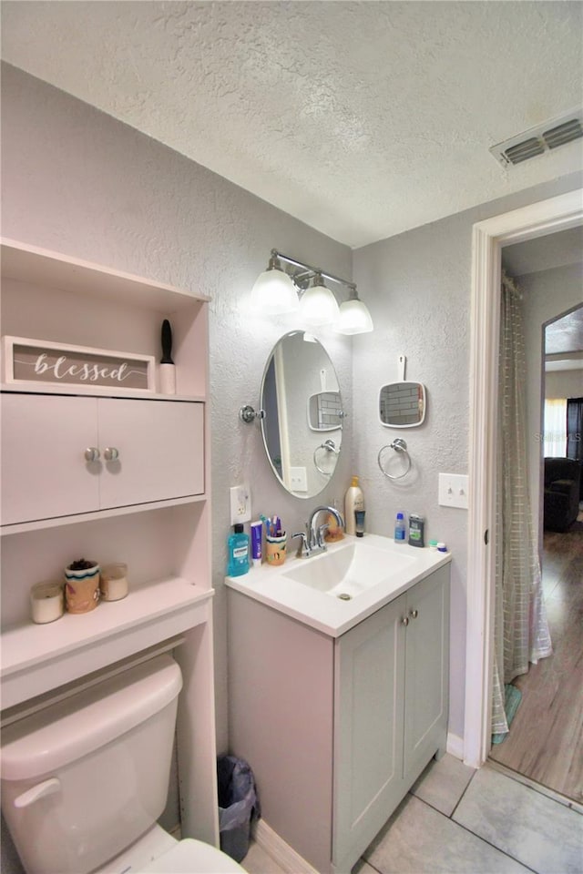 bathroom with hardwood / wood-style floors, a textured ceiling, vanity, and toilet