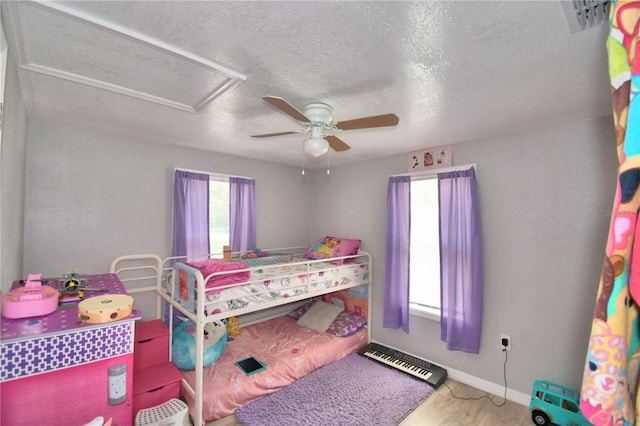 bedroom with a textured ceiling, ceiling fan, and hardwood / wood-style flooring