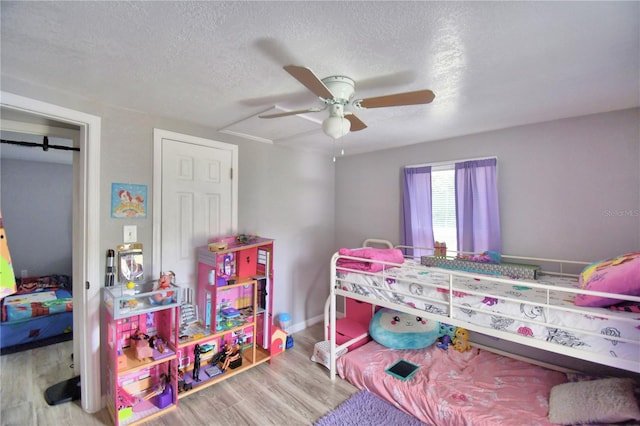 bedroom with a textured ceiling, light hardwood / wood-style floors, and ceiling fan