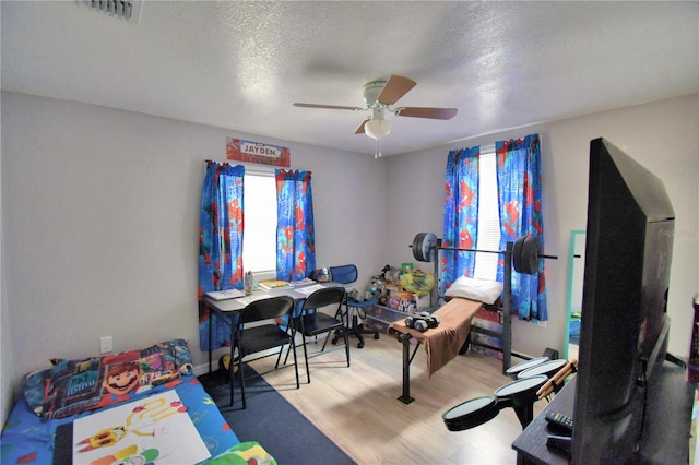 bedroom featuring ceiling fan, a textured ceiling, and light hardwood / wood-style flooring