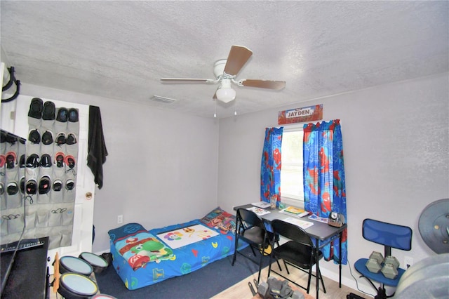 bedroom featuring ceiling fan, hardwood / wood-style floors, and a textured ceiling