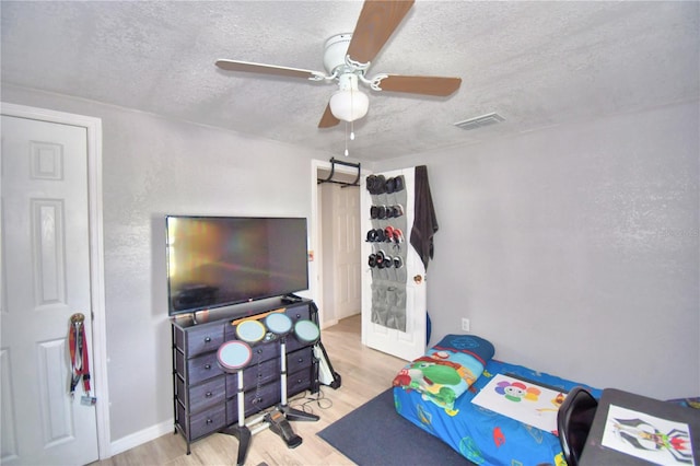 bedroom with light hardwood / wood-style flooring, ceiling fan, and a textured ceiling