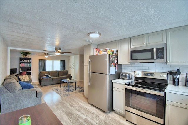 kitchen with tasteful backsplash, stainless steel appliances, a textured ceiling, ceiling fan, and light hardwood / wood-style flooring