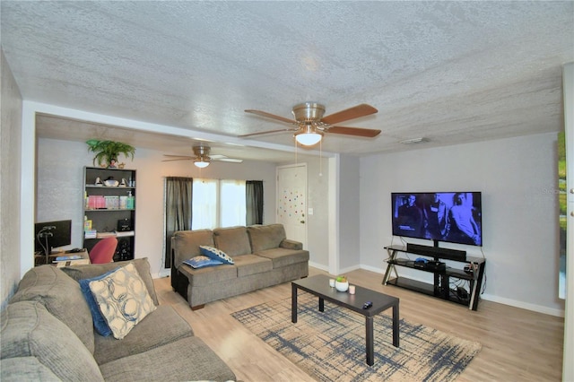 living room featuring light hardwood / wood-style flooring, ceiling fan, and a textured ceiling