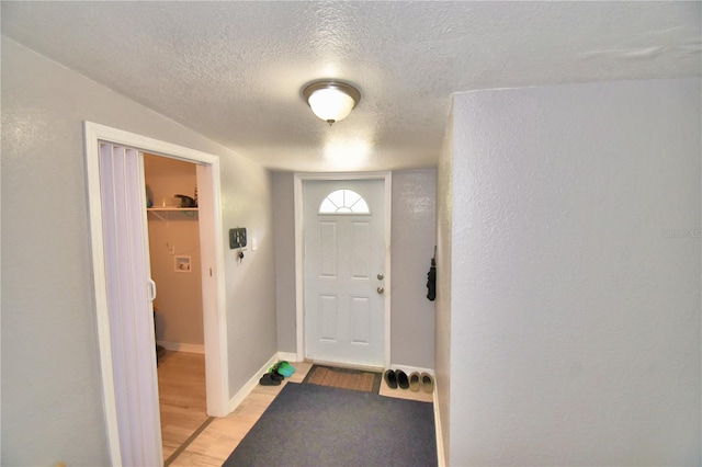 doorway featuring a textured ceiling and light hardwood / wood-style floors