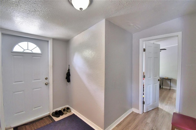 entryway featuring a textured ceiling, vaulted ceiling, and light hardwood / wood-style flooring