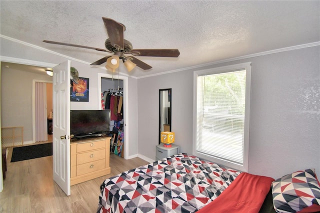 bedroom featuring ceiling fan, ornamental molding, a textured ceiling, a closet, and light hardwood / wood-style floors