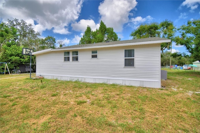 view of side of home featuring cooling unit and a lawn