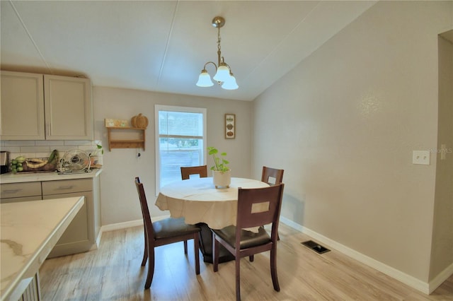 dining space with a notable chandelier, lofted ceiling, and light hardwood / wood-style floors