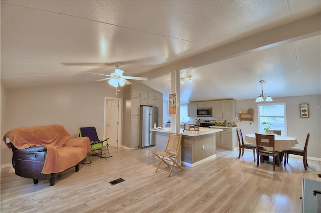 living room with ceiling fan with notable chandelier, vaulted ceiling, and light hardwood / wood-style flooring