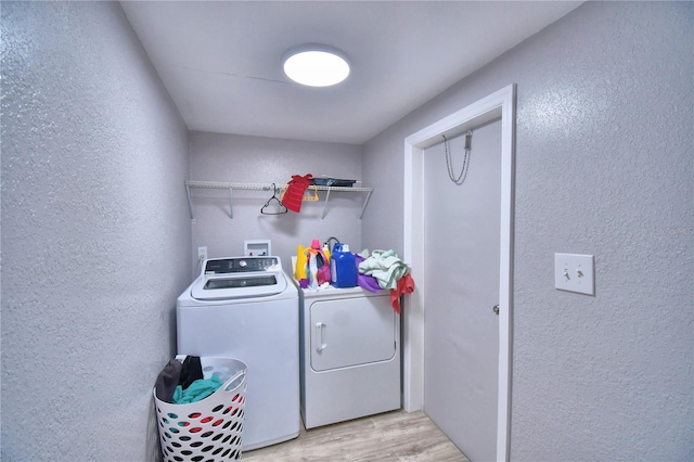 clothes washing area with washer and dryer and light hardwood / wood-style flooring