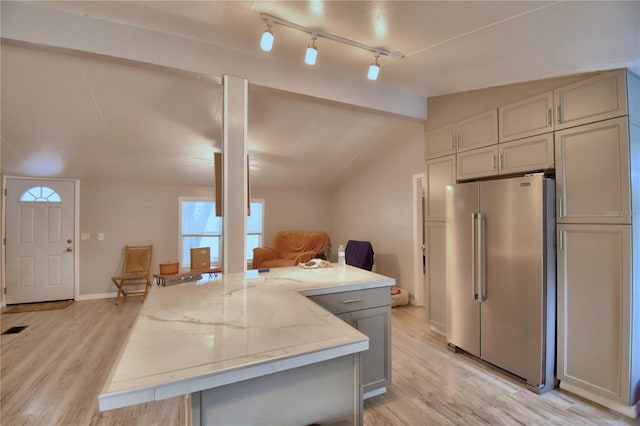 kitchen with light stone countertops, light wood-type flooring, lofted ceiling, and high end refrigerator