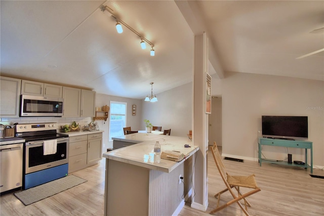 kitchen featuring vaulted ceiling, stainless steel appliances, kitchen peninsula, and light hardwood / wood-style flooring