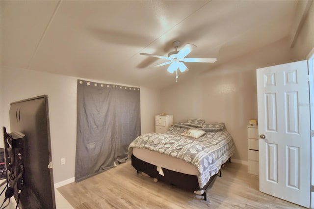 bedroom featuring light wood-type flooring, vaulted ceiling, and ceiling fan