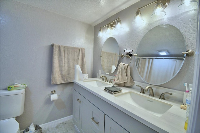 bathroom with a textured ceiling, vanity, and toilet