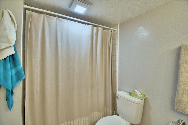 bathroom featuring a shower with curtain, a textured ceiling, and toilet