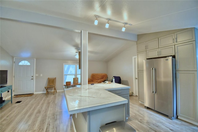 kitchen with light stone counters, light hardwood / wood-style floors, lofted ceiling, stainless steel refrigerator, and ceiling fan