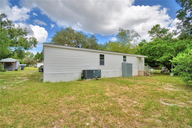 rear view of house featuring a lawn and cooling unit