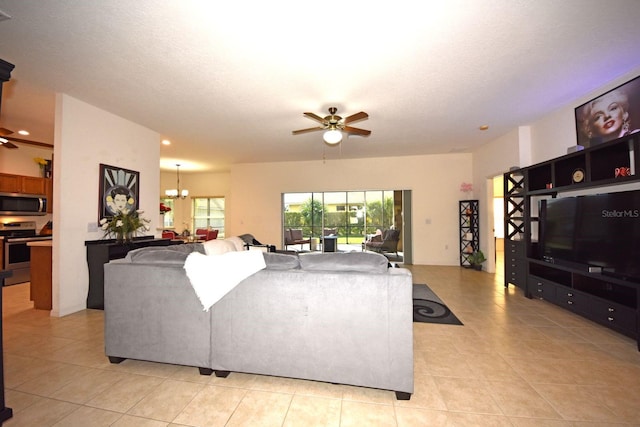 living room with ceiling fan with notable chandelier, a textured ceiling, and light tile patterned floors