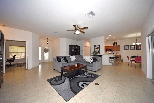 tiled living room featuring ceiling fan with notable chandelier and a textured ceiling