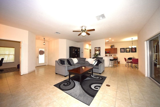 living room with ceiling fan with notable chandelier, a textured ceiling, and light tile patterned floors