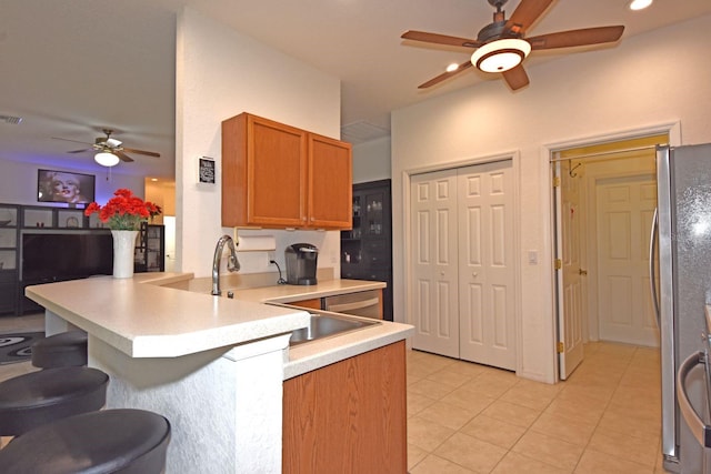 kitchen featuring kitchen peninsula, light tile patterned floors, stainless steel appliances, ceiling fan, and sink