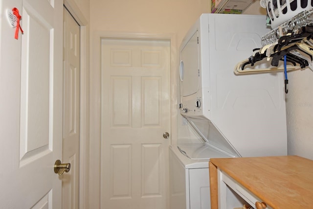 clothes washing area with stacked washing maching and dryer