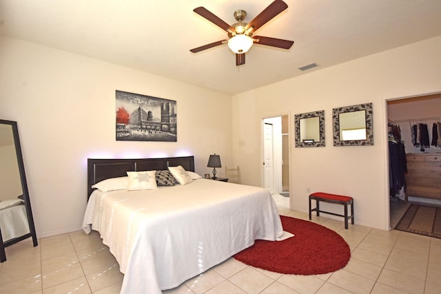 tiled bedroom featuring ceiling fan, a closet, and a walk in closet