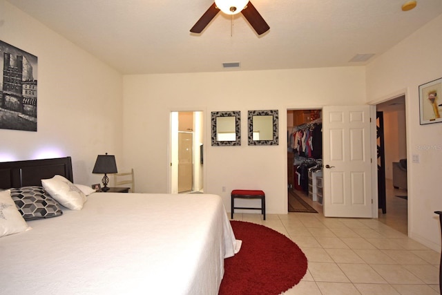 bedroom with a closet, light tile patterned flooring, connected bathroom, a walk in closet, and ceiling fan