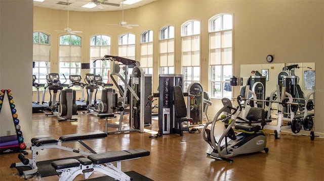 gym with a towering ceiling, dark hardwood / wood-style floors, and ceiling fan