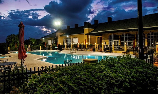 pool at dusk with a patio area