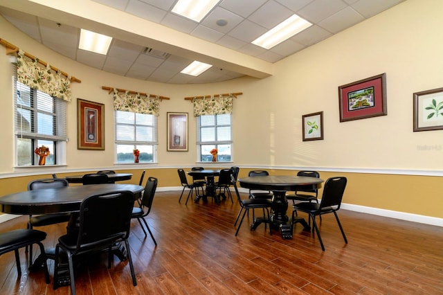 dining space with plenty of natural light, a drop ceiling, and hardwood / wood-style flooring