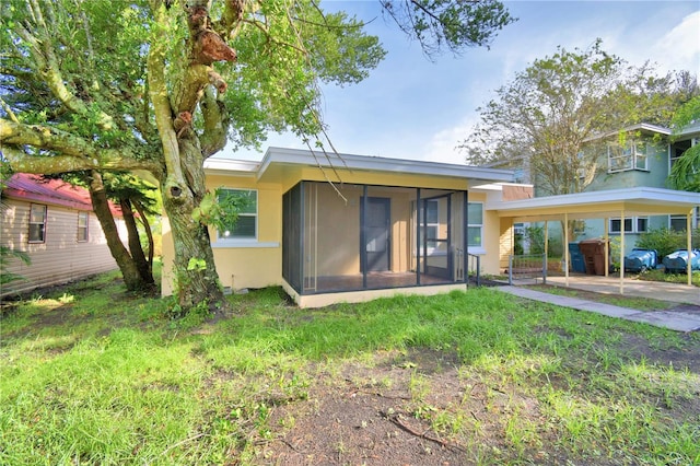 back of property featuring a sunroom and a carport