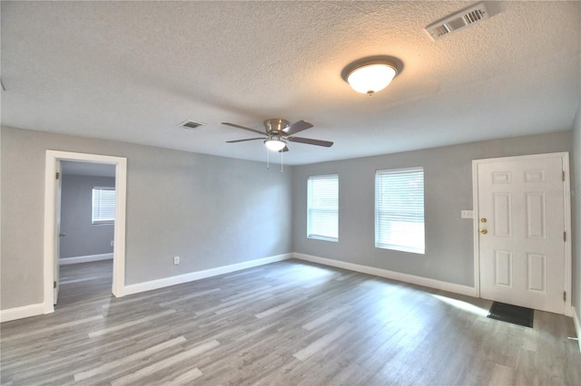 spare room with light wood-type flooring, a textured ceiling, and ceiling fan