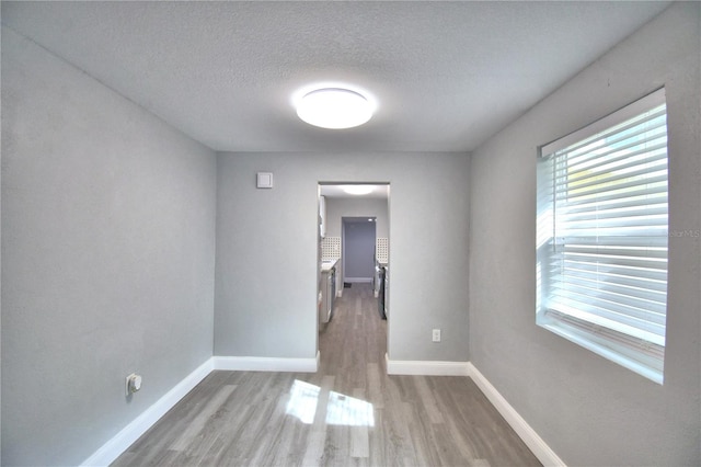 unfurnished room with light hardwood / wood-style floors and a textured ceiling