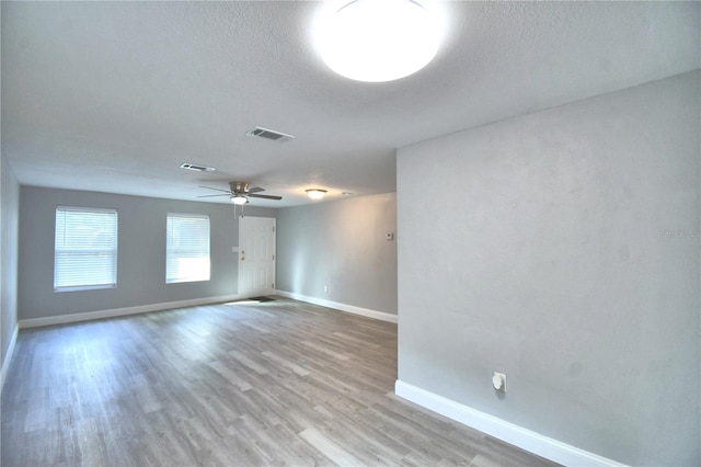 empty room featuring light hardwood / wood-style flooring, ceiling fan, and a textured ceiling