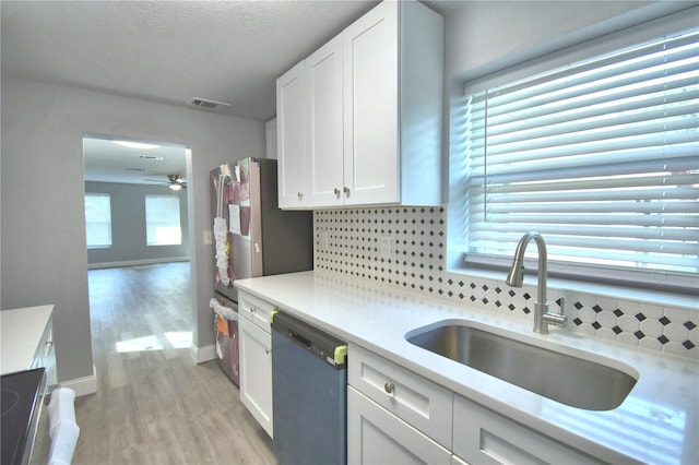 kitchen with tasteful backsplash, white cabinets, a healthy amount of sunlight, stainless steel dishwasher, and sink