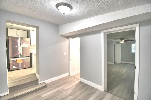 spare room with a textured ceiling, light hardwood / wood-style floors, and ceiling fan