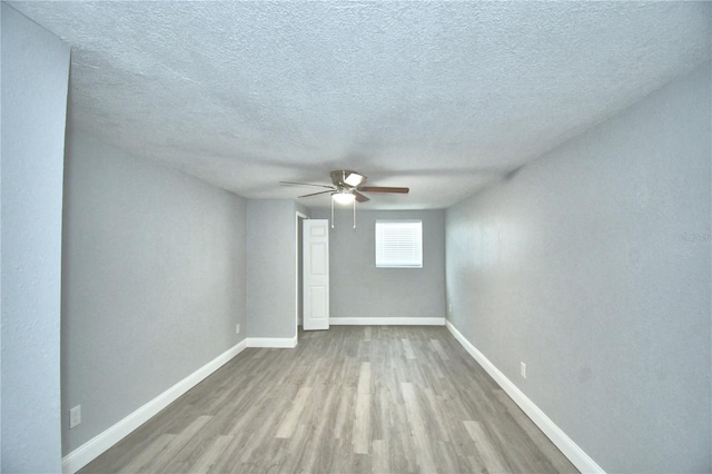 unfurnished room featuring light wood-type flooring, ceiling fan, and a textured ceiling